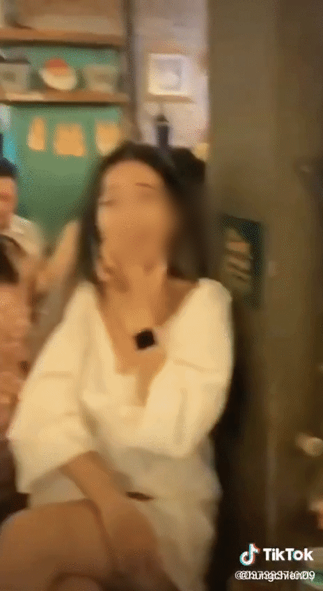 Birthday group moves cake away, streamer finishes the cream on her hand and laughs loudly.