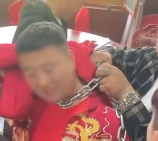 Groom struggling with a heavy iron chain around his neck on his wedding day
