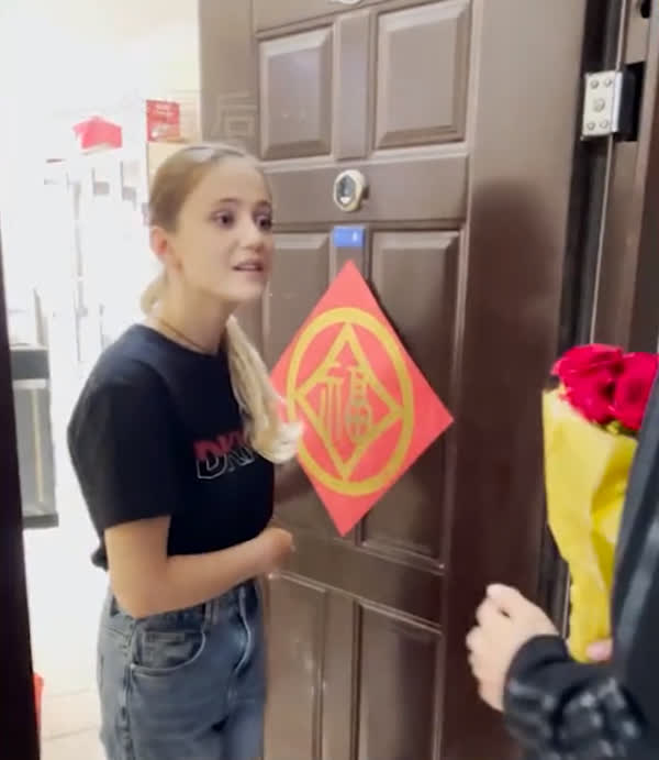 The guy knocks on his neighbor's door with flowers