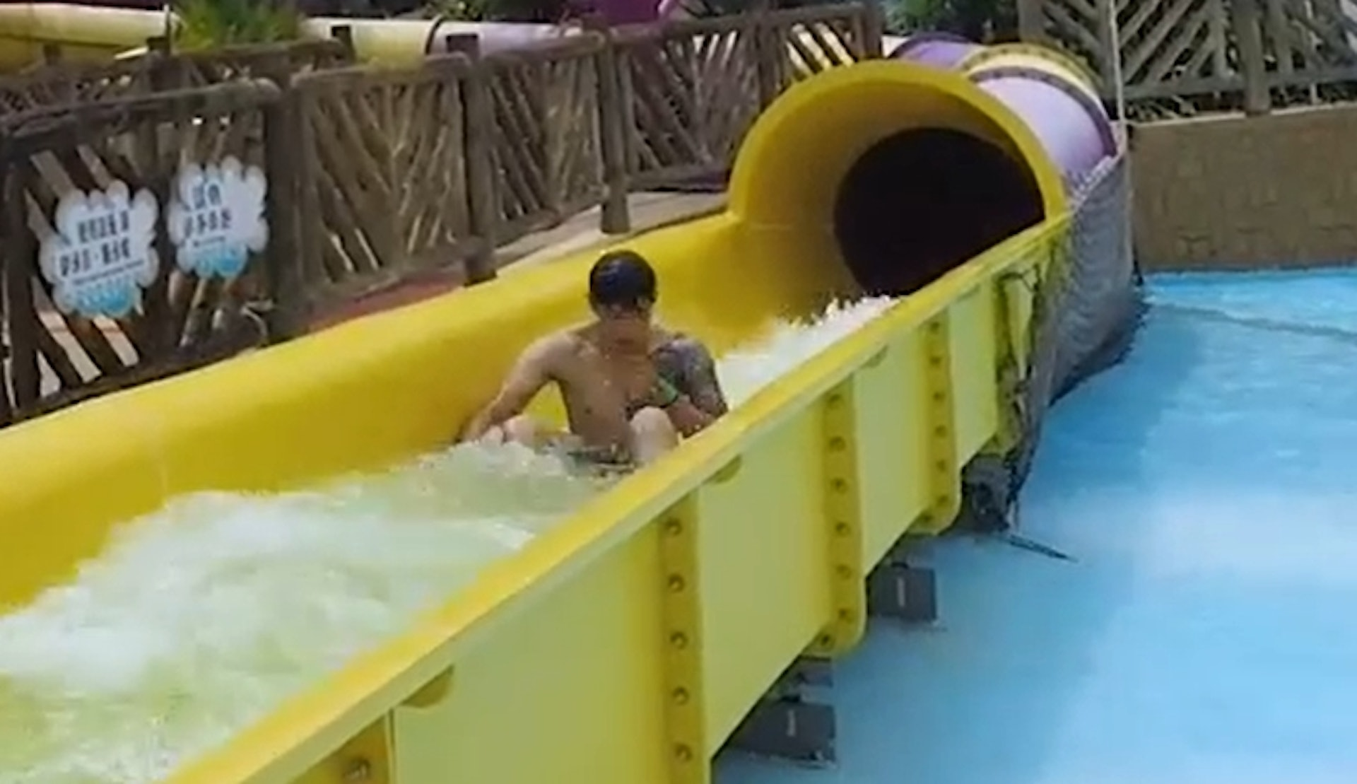 Muscular guy emerging from water slide