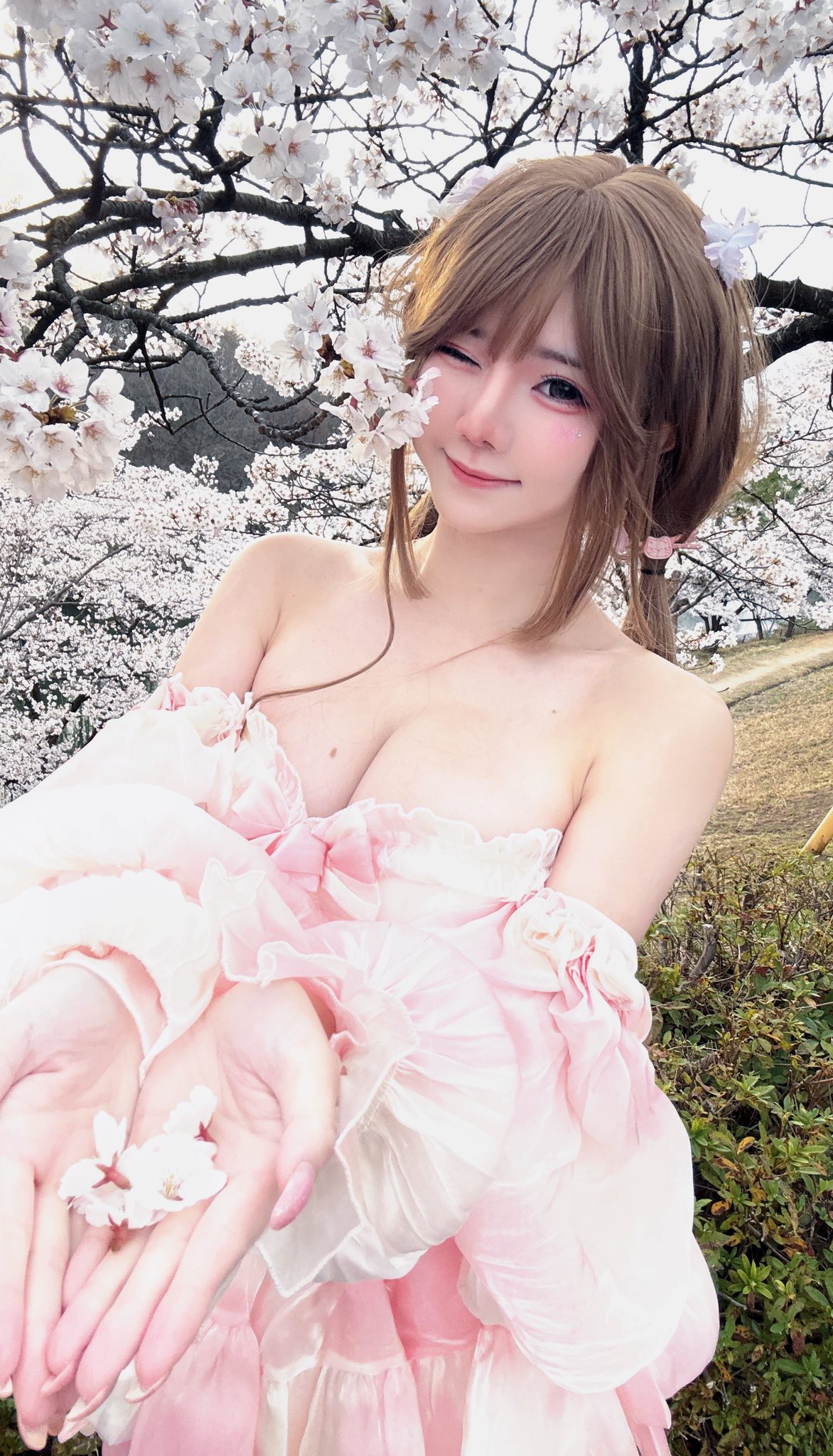 Cosplayer in pastel pink dress among blossoms