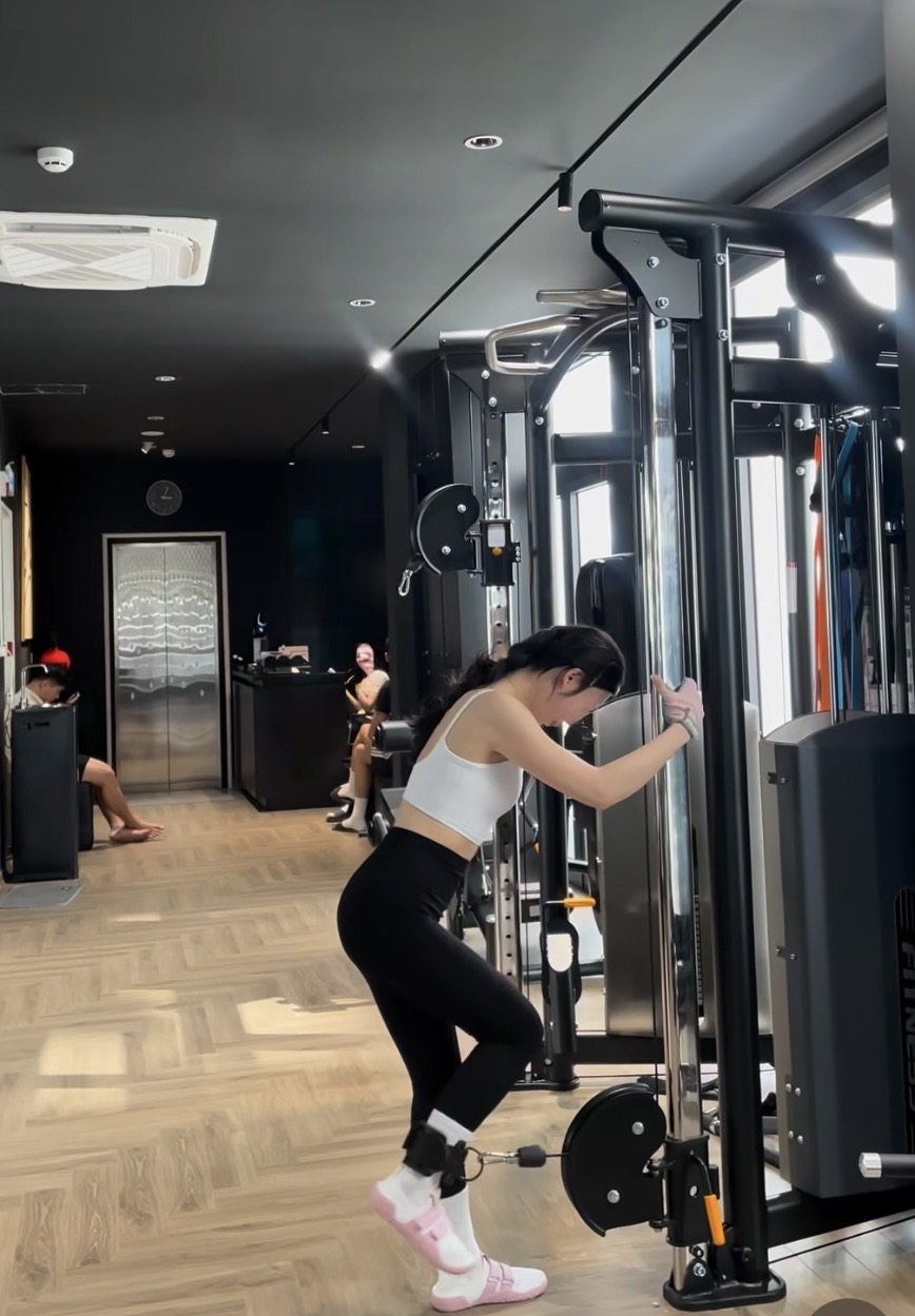 Male personal trainer assisting female gym member