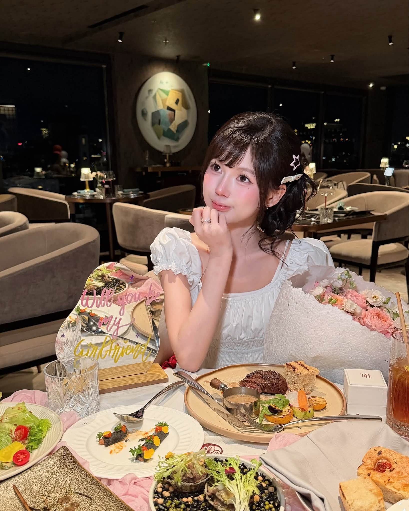 Pun wearing an elegant white square-neck dress with a cute bow clip, shyly covering her face but eyes full of happiness